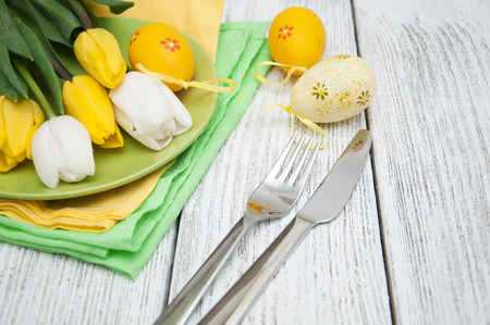 Easter background with yellow tulips and colorful eggs over white wooden table. Top view with copy spaceの写真素材