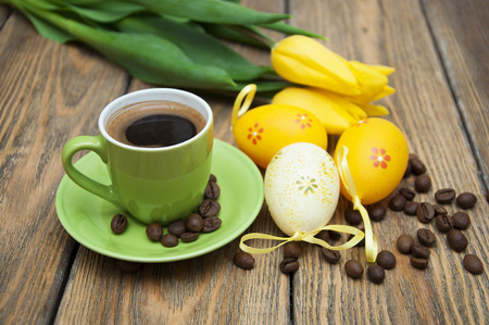 Aromatic coffee with yellow tulips and Easter eggs on a wooden backgroundの写真素材