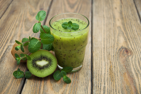 Healthy fresh kiwi smoothie in glass on a wooden backgroundの写真素材
