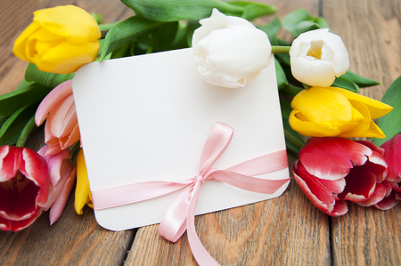 Tulips with gift card and ribbon on a wooden backgroundの写真素材