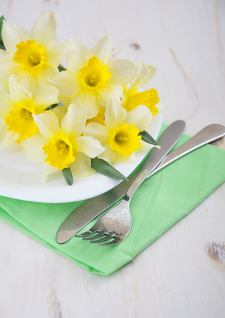 Festive dining table setting with spring narcissus flowers on wooden backgroundの写真素材