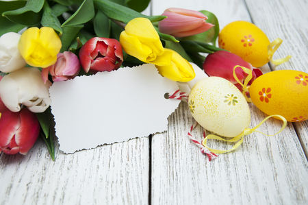 Easter gift card with tulips and Easter eggs on a wooden backgroundの写真素材