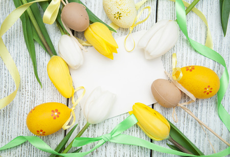 Fresh tulips, easter eqqs and empty card for your text on a wooden background. Top view with copy spaceの写真素材