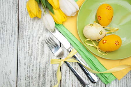 Easter background with yellow tulips and colorful eggs over white wooden table. Top view with copy spaceの写真素材