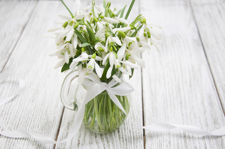 Beautiful snowdrops in a vase on a wooden backgroundの写真素材