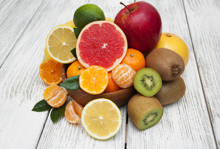 Fresh juicy citrus fruits in a plate on a wooden backgroundの写真素材