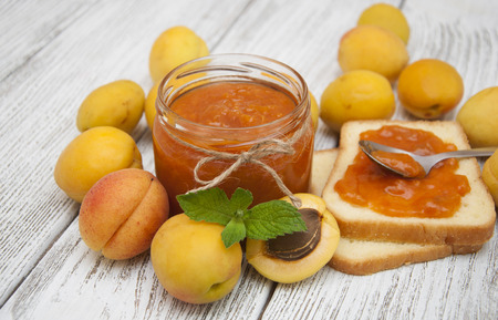 Fresh apricot jam in a jar with mint,with sandwiches and apricot fruits on wooden tableの写真素材