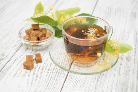 A cup of herbal linden tea with flowers on a wooden backgroundの写真素材