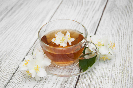 A cup of jasmine tea with jasmine flowers on a wooden backgroundの写真素材