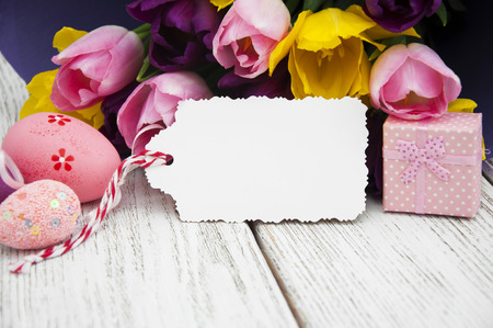 Tulip bouquet with blank greeting card and easter eggs on a wooden background
の写真素材