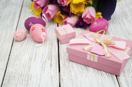 Gift Box, Easter eggs and bouquet of tulips on wooden backgroundの写真素材