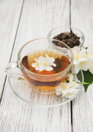 A cup of jasmine tea with jasmine flowers on a wooden backgroundの写真素材