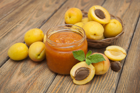 Fresh apricot jam in a jar with mint and apricot fruits on wooden tableの写真素材