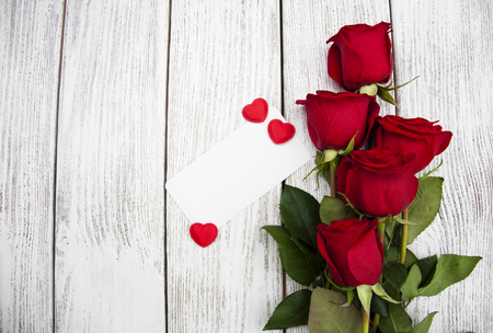 Red roses with greeting card on a wooden backgroundの写真素材