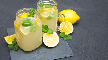Homemade lemonade with fresh lemon and mint on a stone backgroundの写真素材