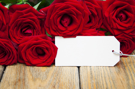 Beautiful bouquet of roses with a greeting card on a wooden backgroundの写真素材