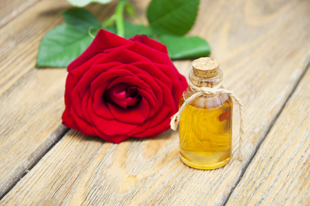 Bottles essence aroma oil with roses and petals on wooden background. Transparent Little Bottlesの写真素材