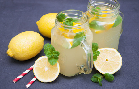 Homemade lemonade with fresh lemon and mint on a stone backgroundの写真素材