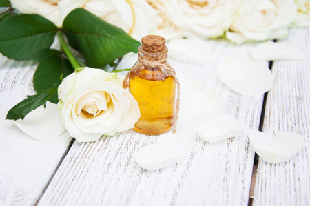Bottles essence aroma oil with roses and petals on wooden background. Transparent Little Bottlesの写真素材
