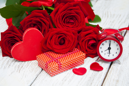 Beautiful bouquet of roses with a gift box on a wooden backgroundの写真素材