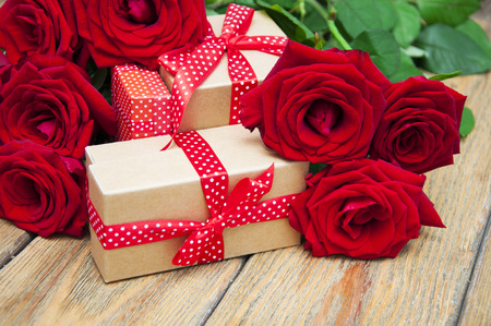 Beautiful bouquet of roses with a gift box on a wooden backgroundの写真素材