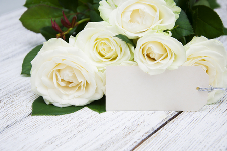 Beautiful bouquet of roses with a greeting card on a wooden backgroundの写真素材