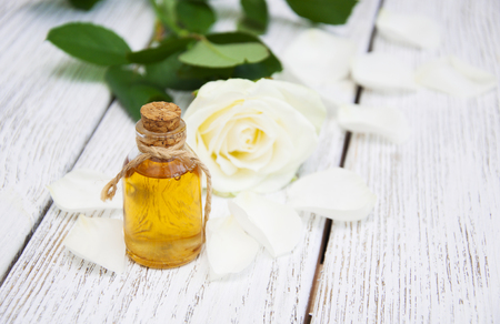 Bottles essence aroma oil with roses and petals on wooden background. Transparent Little Bottlesの写真素材