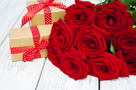 Beautiful bouquet of roses with a gift box on a wooden backgroundの写真素材
