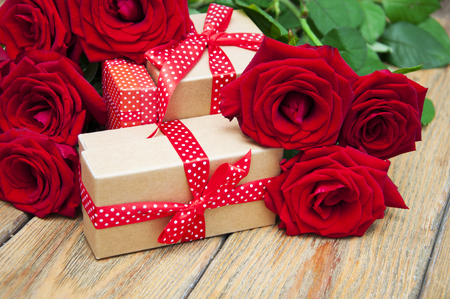 Beautiful bouquet of roses with a gift box on a wooden backgroundの写真素材