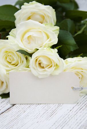 Beautiful bouquet of roses with a greeting card on a wooden backgroundの写真素材