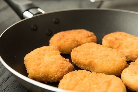 Cooked tasty chicken nuggets in black frying-panの写真素材