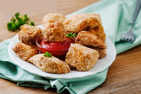 Chicken nuggets on the white plate with tomato sauce
