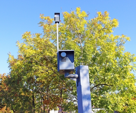 Traffic speed monitoring camera, against a bright blue sky 