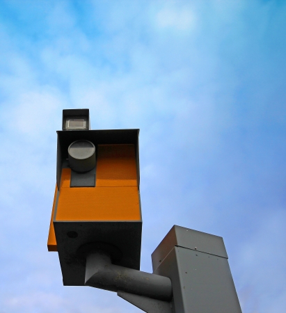A traffic speed monitoring camera, against a bright blue sky 