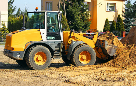 Wheel loader Excavator unloading sand with water during earth moving works at construction site