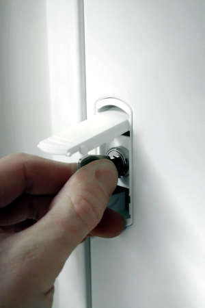 Hand unloking the fuse box  with a key.の写真素材