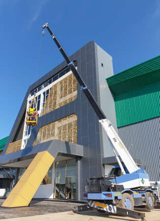 The crane lifted the workers to clean the factory building.の写真素材