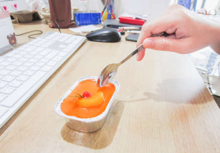 Office workers eat orange cake in the afternoon on their desksの写真素材