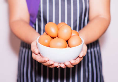 A woman holding fresh eggs in white bowl .の写真素材