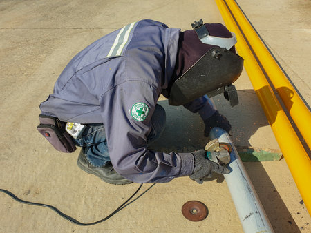 The technician uses a grinding stone to grind steel pipes on the construction site.の写真素材