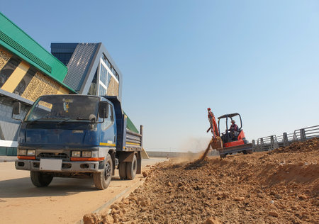 A small backhoe is adjusting the topsoil for landscaping.