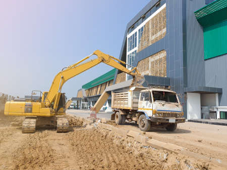 The backhoe digs up the garden soil in the truck for adjust landscape.の写真素材