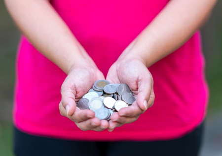 Concept of saving by using coins in the hands of people.の写真素材
