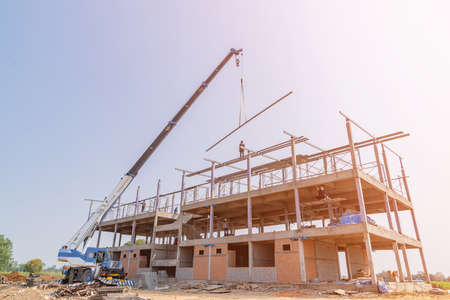 Crane lifting steel structure roof dormitory in the middle of the field.