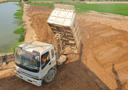 Dumpers pour soil into the edge of the pond to make roads.