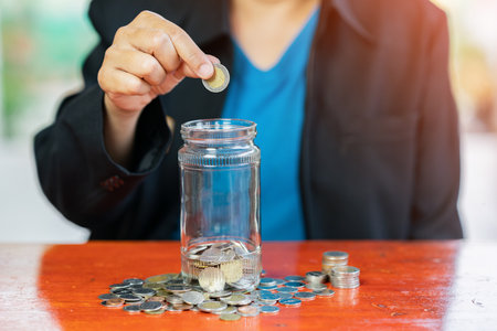 Put coins in a glass bottle, another savings method on out of focus background.の写真素材