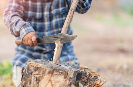 A man is sharpening a pole wood to make a tent on out of focus background.の写真素材