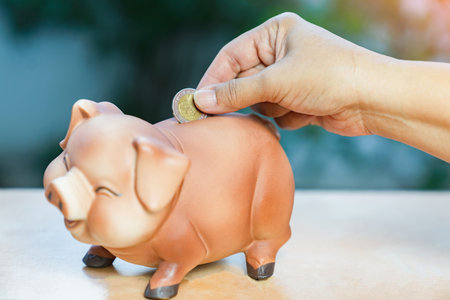 woman puts coins into a piggy bank to create a saving habit.の写真素材