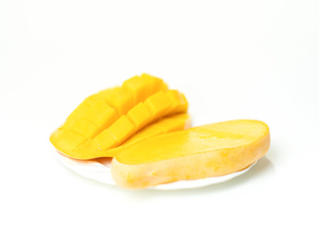 Golden mango slices on a white plate.isolate white background.の写真素材