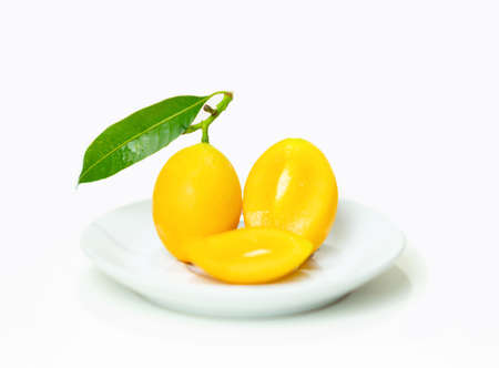 Ripe marian plum cut on plate isolate white background.の写真素材